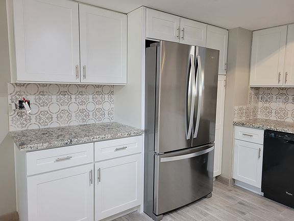 Brand new large stainless steel refrigerator. Pantry cabinet next to refrigerator.
