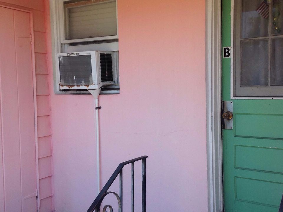 Front door (back of house, west side of building). Opens into kitchen. (A/C moved to bedroom.)