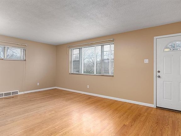 Living room features hardwood, neutral colors and coat closet.