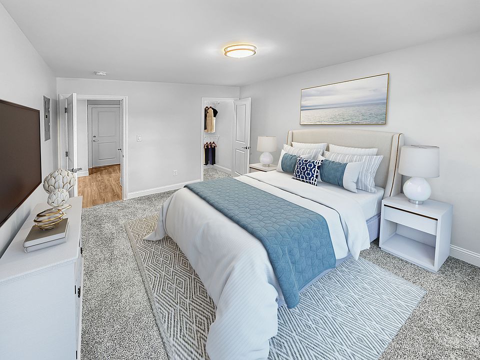 Elegant bedroom featuring a plush bed with blue accents, carpeted floor, and modern decor, offering a serene ambiance.