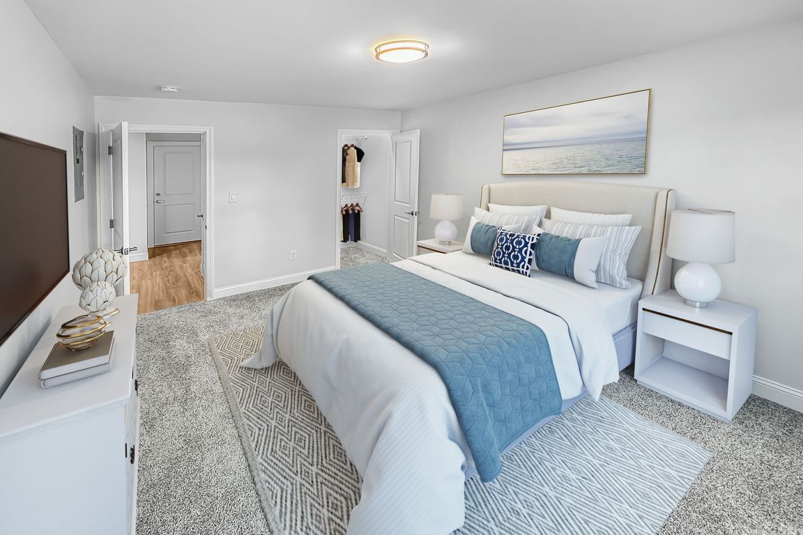Elegant bedroom featuring a plush bed with blue accents, carpeted floor, and modern decor, offering a serene ambiance.