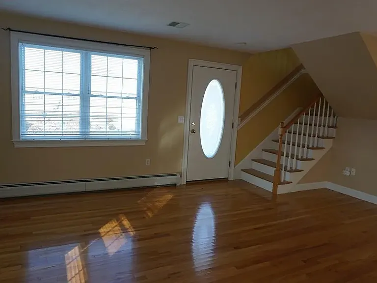 Living room with front door entrance. This room has been painted to a more neutral color as seen in other photos