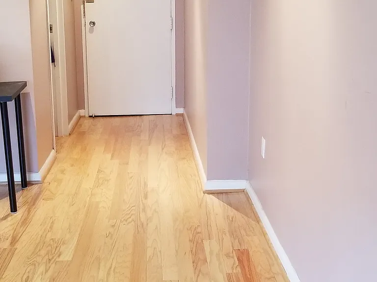 View from the living room to the front door. Door on the left is through the walk in closet to the bathroom. Kitchen table is round and can be replaced with a square table.