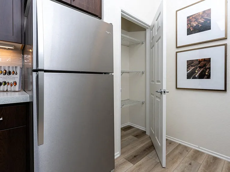 Spacious Kitchen Pantry with Open Shelving and Stainless Steel Refrigerator