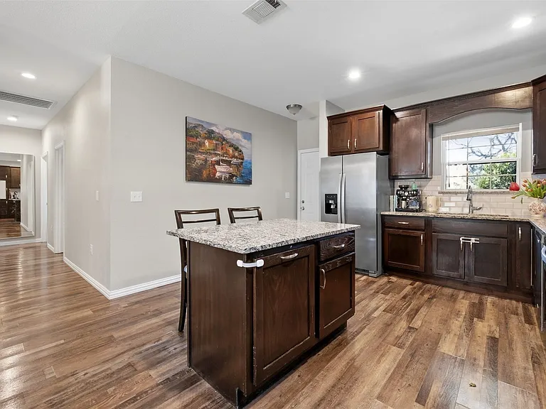 Kitchen featuring wood-finish flooring, dark wood cabinetry, and granite countertops