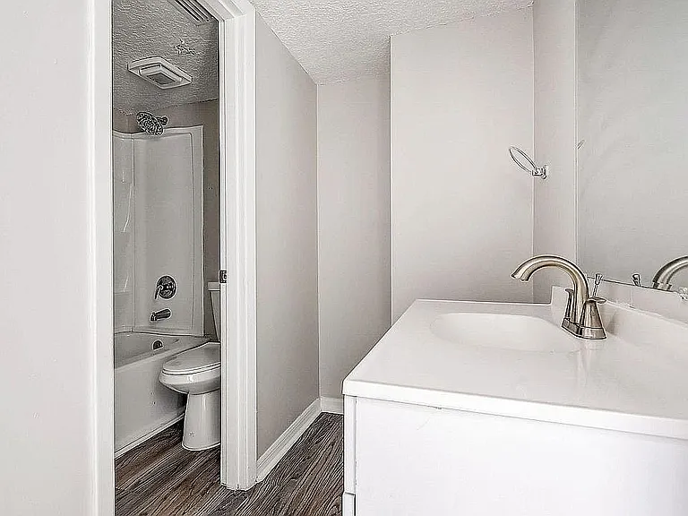 Modern and bright bathroom featuring sleek fixtures, a pristine bathtub, and elegant wood flooring.
