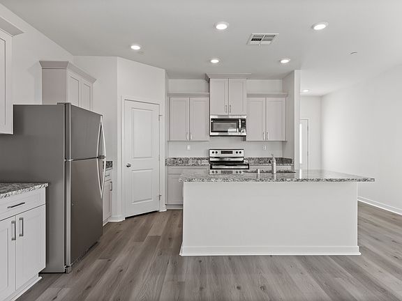 The kitchen has plank flooring and stainless steel appliances.