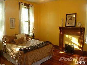master bedroom with hardwood floors and charming fireplace.