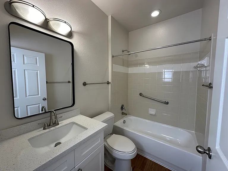 Modern bathroom featuring a sleek vanity, quartz countertop, spacious mirror, and a comfortable bathtub with elegant fixtures. Modern bathroom featuring a sleek vanity, quartz countertop, spacious mirror, and a comfortable bathtub with elegant fixtures.