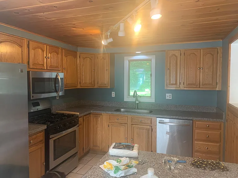 Kitchen with new appliances, counter, sink, faucet, cabinet hardware.