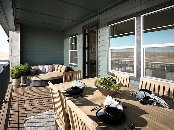 A cozy outdoor patio with wooden furniture, potted plants, and large windows overlooking a scenic la