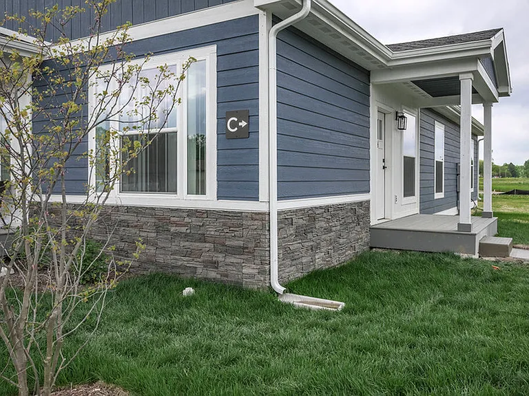 Charming blue house exterior with modern stone accents and lush green lawn.