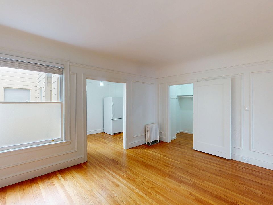 Bright room with hardwood flooring, featuring a window with a blind, and doorways leading to a kitchen and closet space