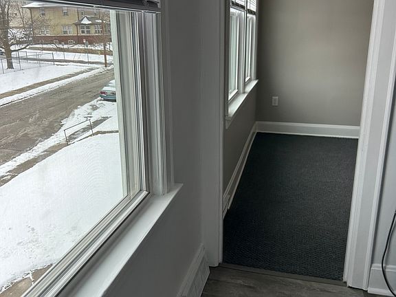 View from the kitchen into the living room with plenty of natural light coming in from windows that face the front of the building.