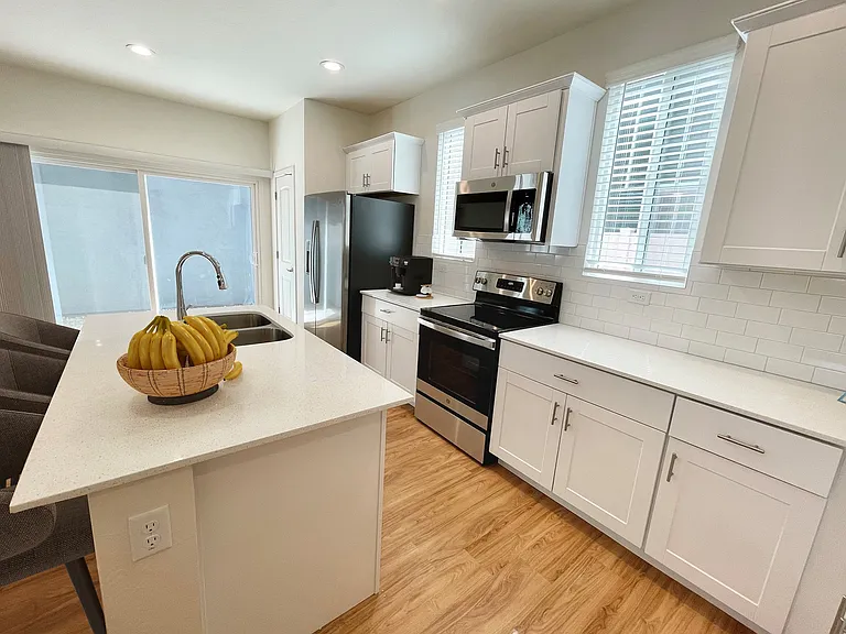 Kitchen facing patio and showcasing gorgeous white subway tile backsplash. This kitchen is designed to be bright and sleek.