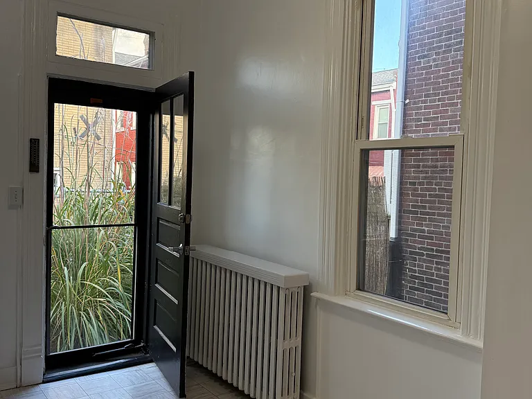 Kitchen door opens directly onto the garden w/ tall grasses, roses, & stunning pink peonies (as well as a privacy fence), perfect for a small outdoor table & 2 or 3 chairs