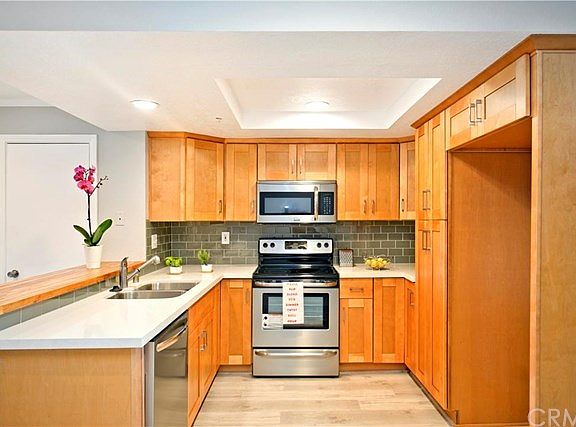 Brand new kitchen with wood like tile flooring and new stainless steel appliances.