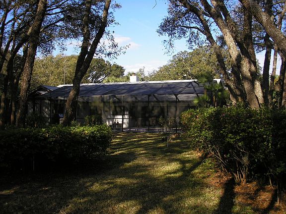 Rear of home from backyard. You see the pool cage, recently rescreened.