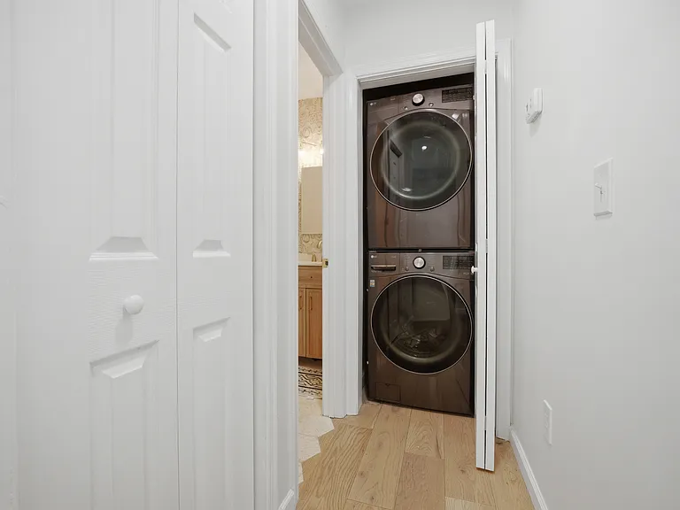 Laundry stack and separate linen closet located in primary bedroom hallway.