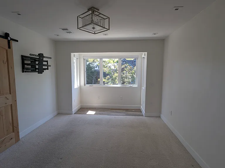 Primary bedroom, has a large alcove with independent lighting, lots of room, barn door access to bathroom and a TV stand premounted.