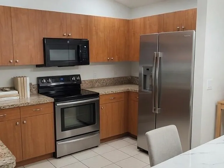 U-shaped kitchen with ample cabinet storage, stone-look counters, and stainless appliances plus an adjacent dining area.