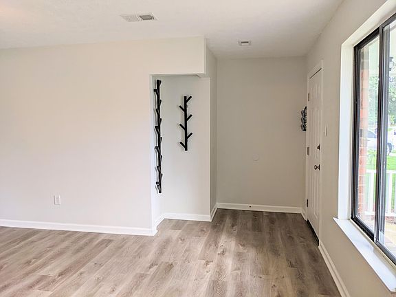 living room looking back at entry and entryway nook to hang coats.
