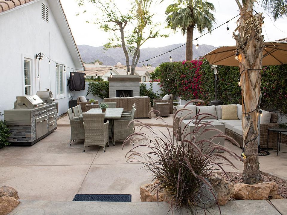 View of the outdoor living space. Gas fireplace with couch, two lounge chairs and coffee table. Dining area. Sectional area with a firepit. All with views of the golf course.