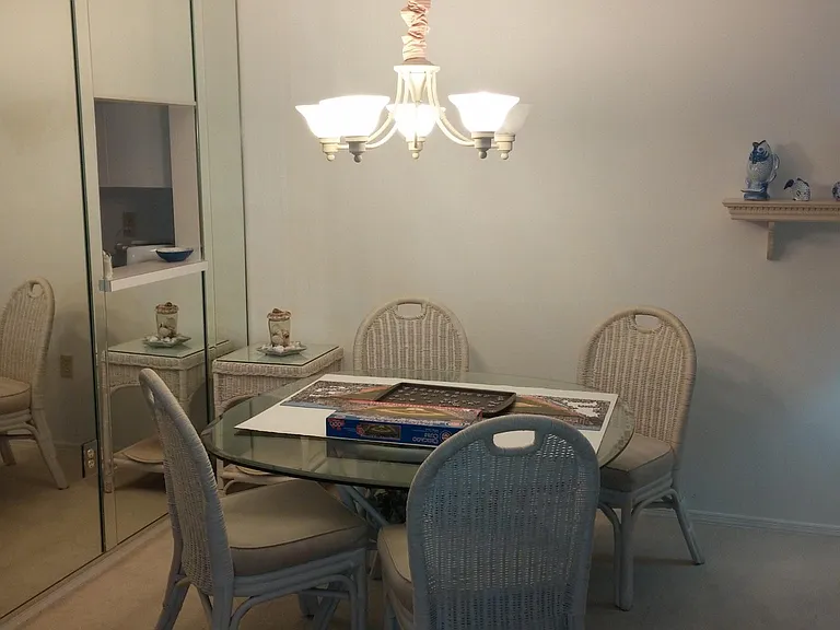 The dining room is a great place for crossword puzzles. Note the floor to ceiling mirrored wall which reflects the water and sunset view. Also the pass-through from the kitchen to the dining room.