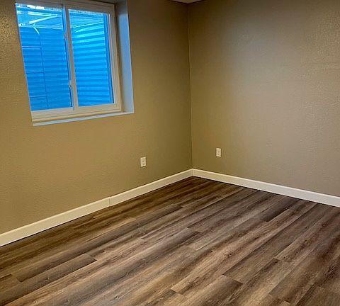 Bedroom 1 with egress window well, ceiling fan, and solid-core door.