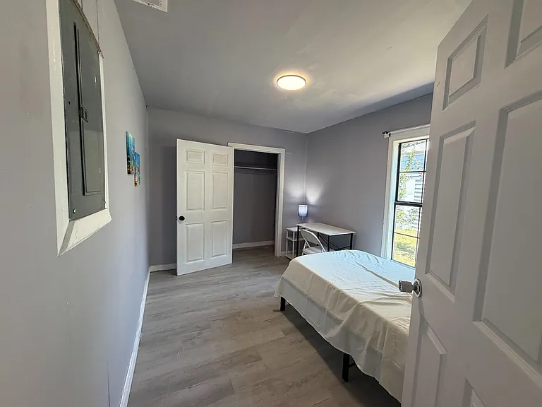 Private bedroom with a bed, desk workspace, and a closet for storage, plus a window for natural light.