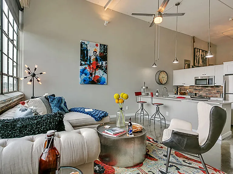 Living room with open concept kitchen, concrete floor, and beautiful white cabinets. Loft style apartment
