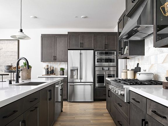 A modern, well-equipped kitchen with dark cabinets, stainless steel appliances, and a sleek, minimal