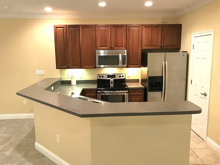 Kitchen with stainless steel refrigerator with ice and water dispenser. Self cleaning glass-top stove/oven.
stainless dishwasher and microwave. The counter top is quartz ( very High end). 
Door leads to the pantry.