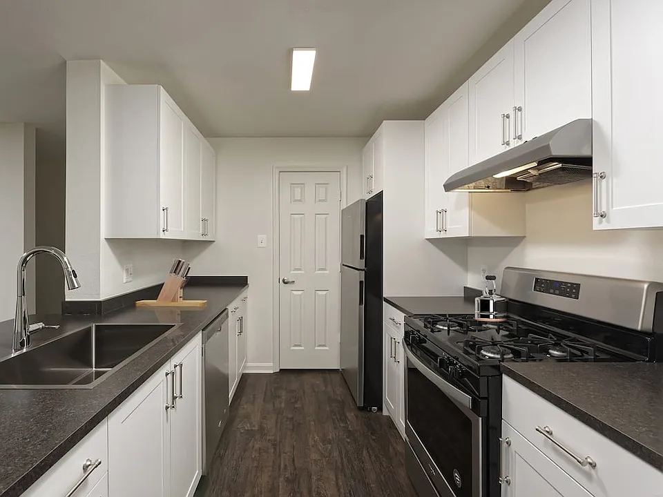 Renovated Package II kitchen with white cabinetry, dark grey laminate countertops, and stainless steel appliances, and hard surface flooring