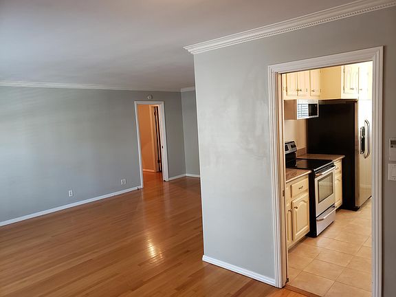 View from dining room to living room with crown molding. Renovated kitchen with new tile floor and top of the line stainless steel appliances to the right.