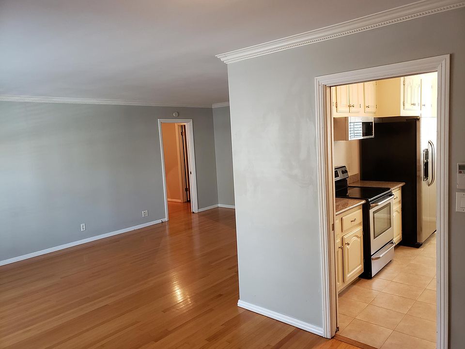 View from dining room to living room with crown molding. Renovated kitchen with new tile floor and top of the line stainless steel appliances to the right.