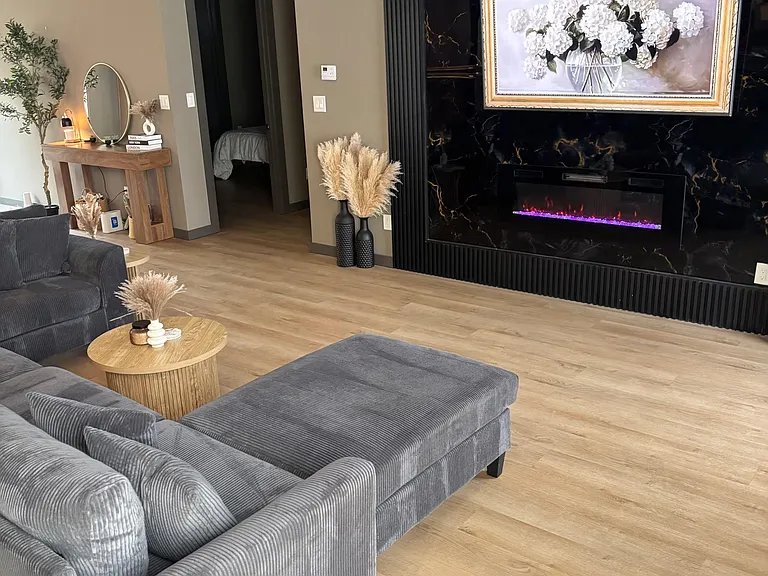 Stylish living room with sectional seating, a statement fireplace feature wall, and open flow to the hallway.
