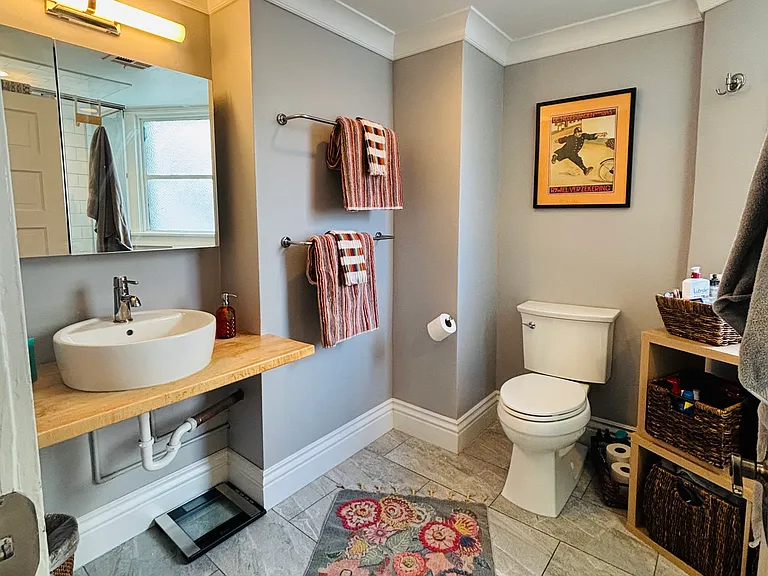 Step into a bathroom where function meets fashion in a thoughtfully designed space. The centerpiece is a designer sink set atop a warm, wood counter that adds charm and character.