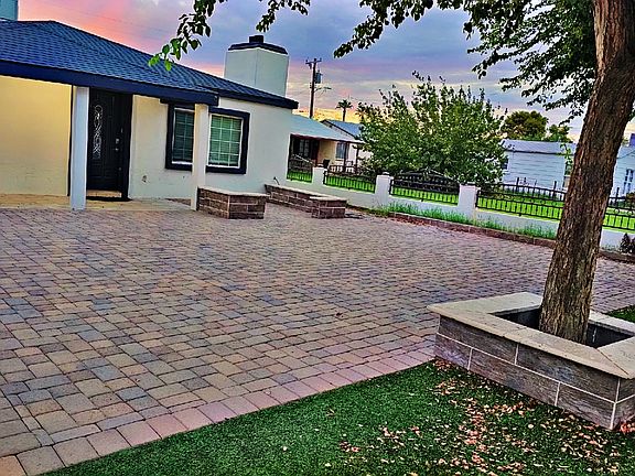 Spacious paver courtyard with mature tree and custom planter boxes _ perfect blend of shade, style, and outdoor charm. Ideal for gatherings or quiet evenings under Arizona skies.