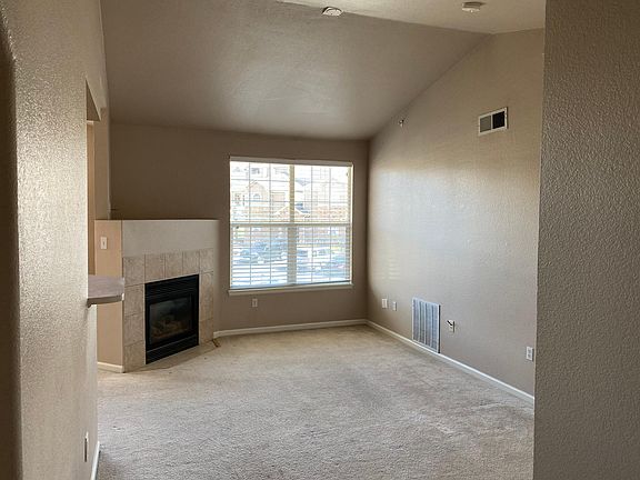 Living room with gas fireplace, large windows and vaulted ceilings create a spacious and bright living area.