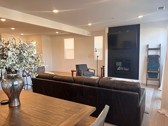 Family/Great Room with gas fireplace. Leather sofa, ottoman/coffee table, smart tv, area rug, chair, side table, standing lamp, blanket ladder with blankets, etc.