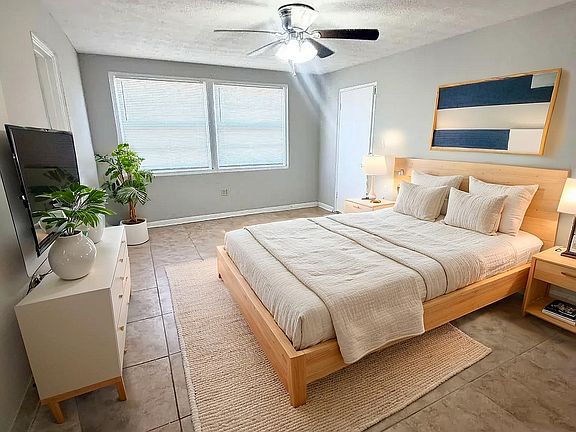 Bright and inviting bedroom with a modern design, featuring a cozy wooden bed, contemporary artwork, and serene natural lighting.