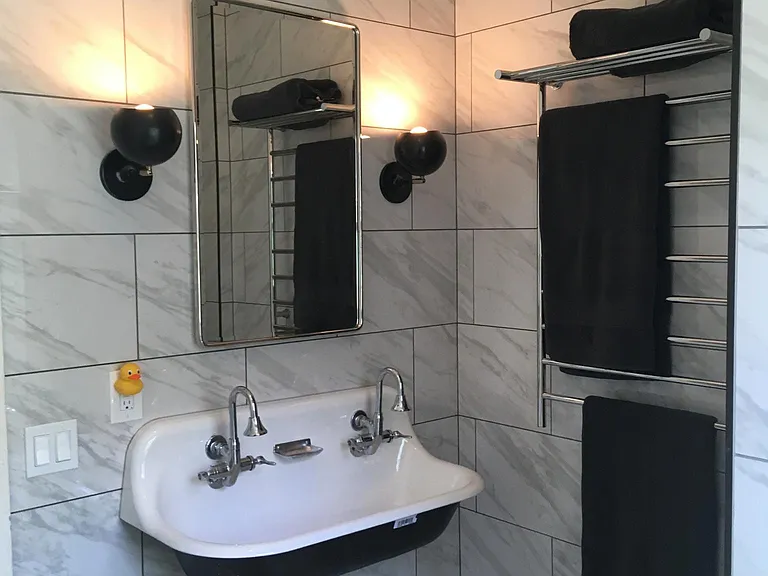 Newly rehabbed bath with tile floors and floors, heated towel rack, double faucet sink and School House lighting fixture. Bathroom cabinet extra-long and deep for plentiful storage.
