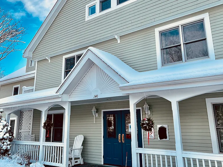 Front door, with porch, to lobby and elevator. #312 master bedroom window showing above pinnacle of porch roof.