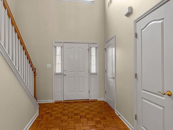 Timeless parquet entry. Coat closet, 1/2 bath, soaring ceilings, and architectural shelving