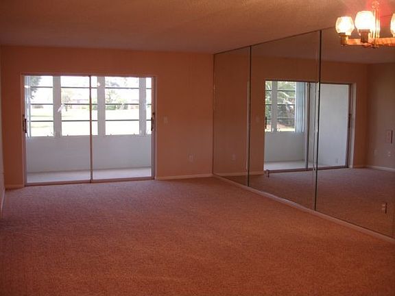 Your living room with mirrored wall looking through enclosed lanai to lush....