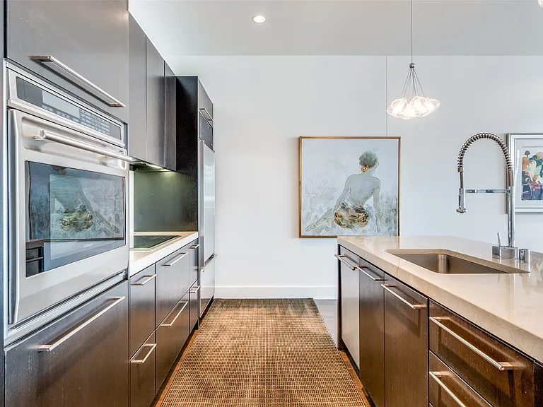 Kitchen featuring hanging light fixtures, stainless steel appliances, light stone countertops, recessed lighting, and modern cabinets