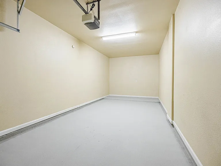 Spacious and clean garage space with high ceiling and sturdy door opener, perfect for parking or storage. Spacious and clean garage space with high ceiling and sturdy door opener, perfect for parking or storage.