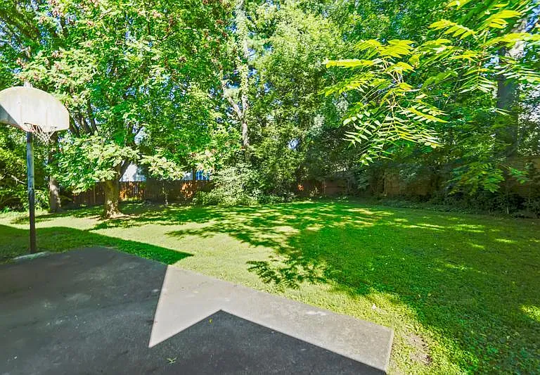 Fenced in backyard with small basketball court / patio area