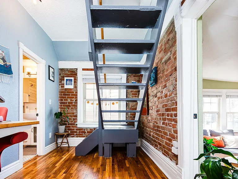 Office nook with exposed brick and stairs to bedroom 2